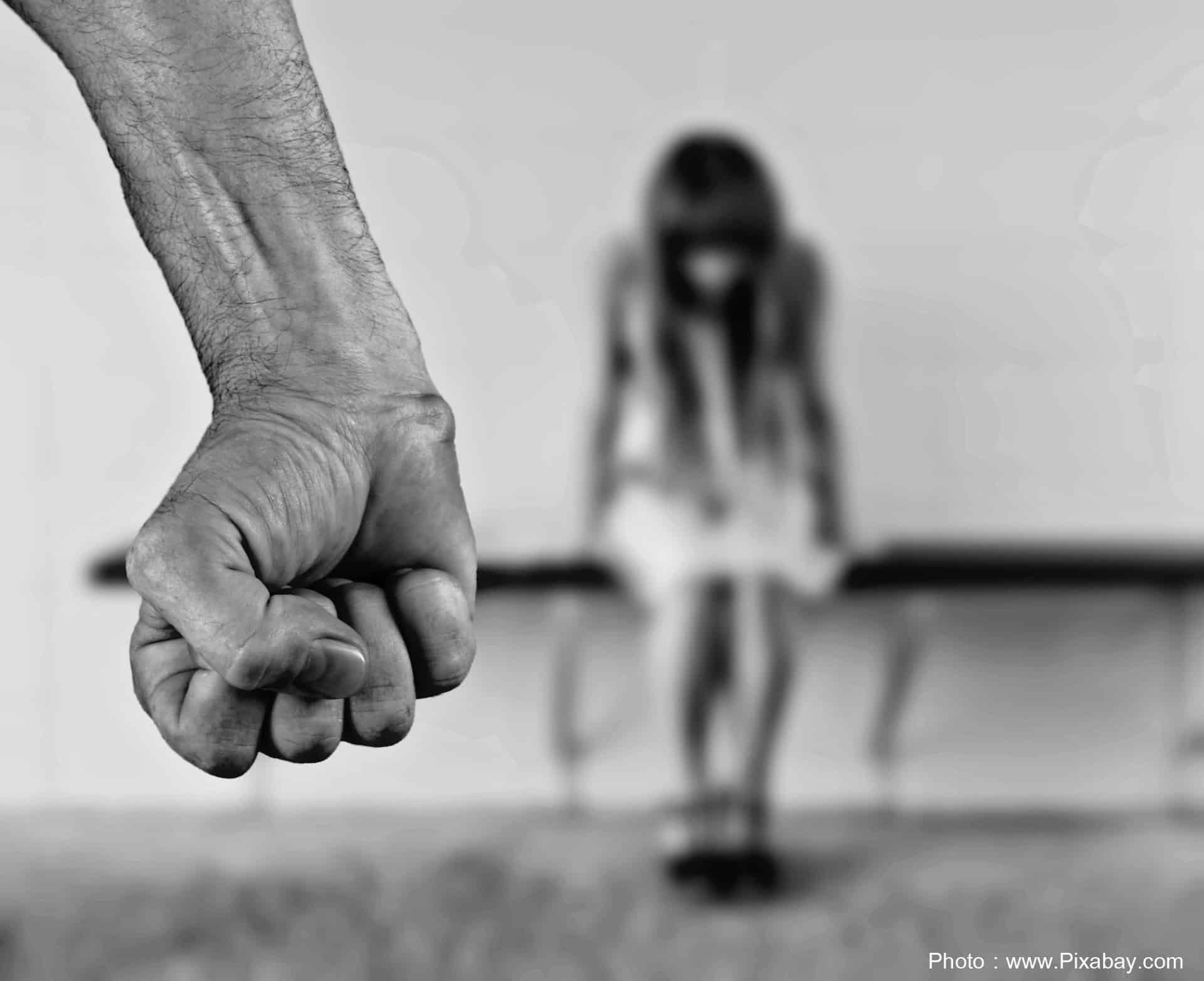 Man holding a tight fist with woman faced down in the background