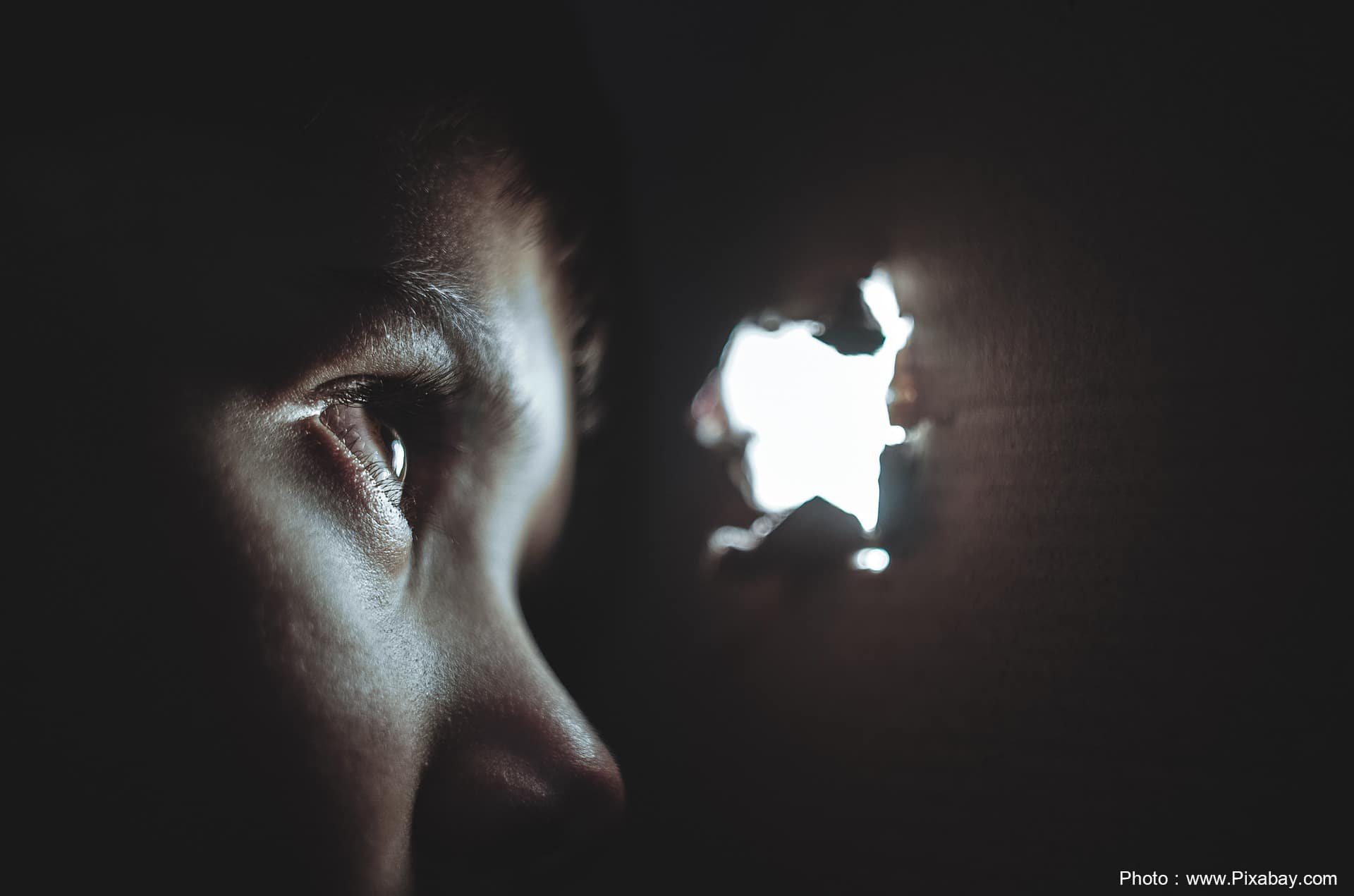 Young child hiding looking through a box