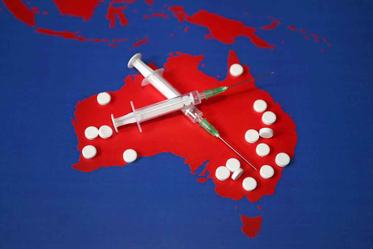 outline of a map of Australia with crossed syringes and pills scattered on it