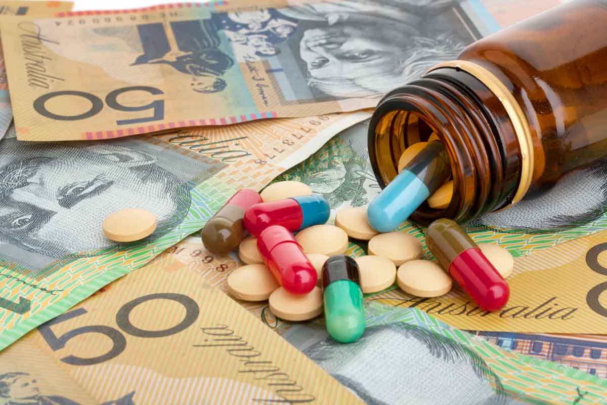 Bottle of pills spilled out onto a stack of Australian dollars