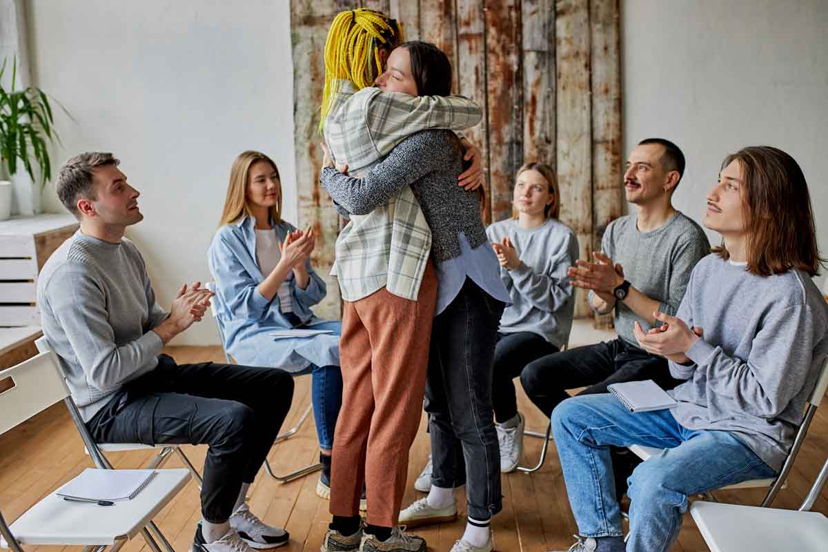 Two women hugging each other at a group therapy meeting