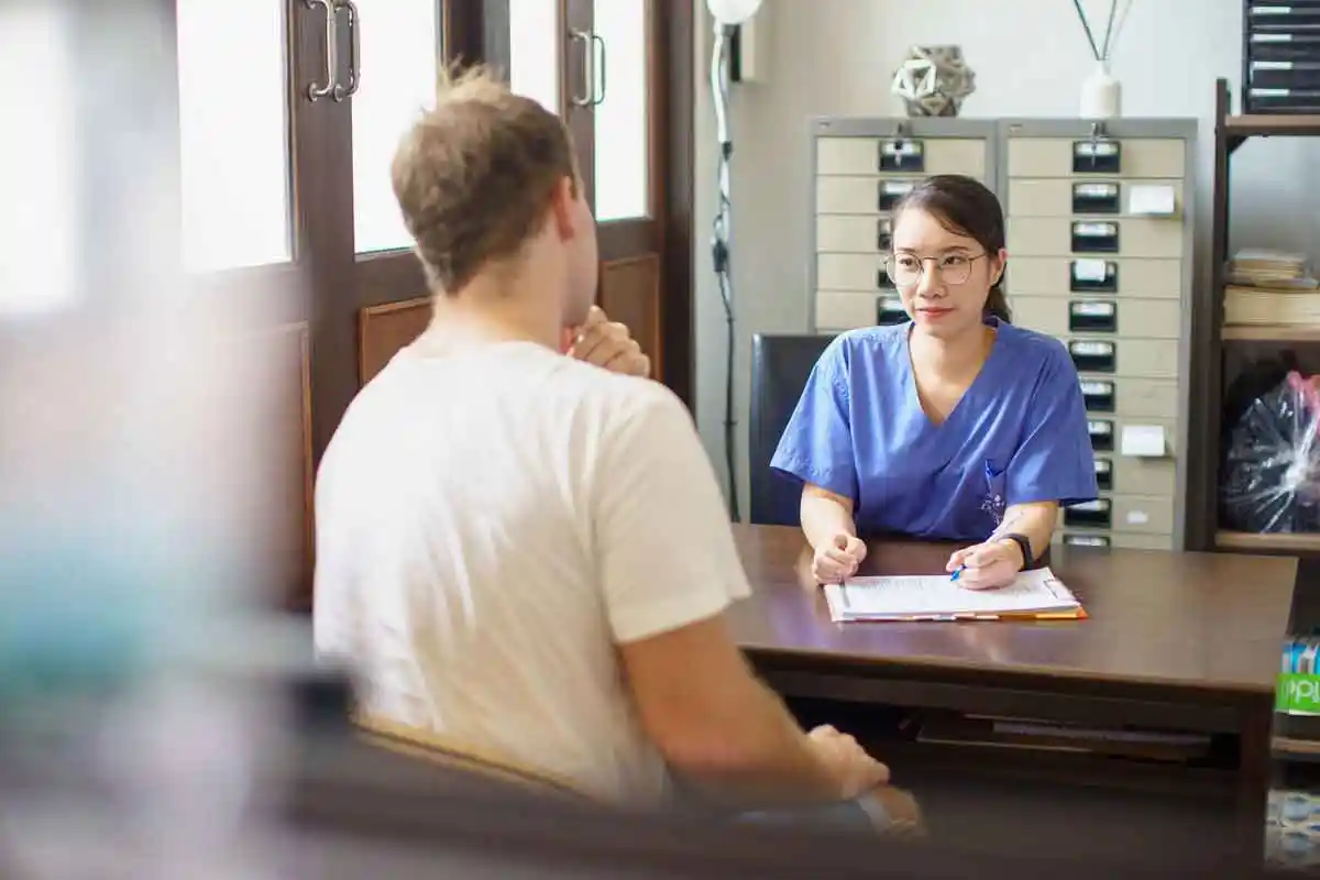 A nurse speaking with a client across a desk and taking notes in an office setting at The Dawn.