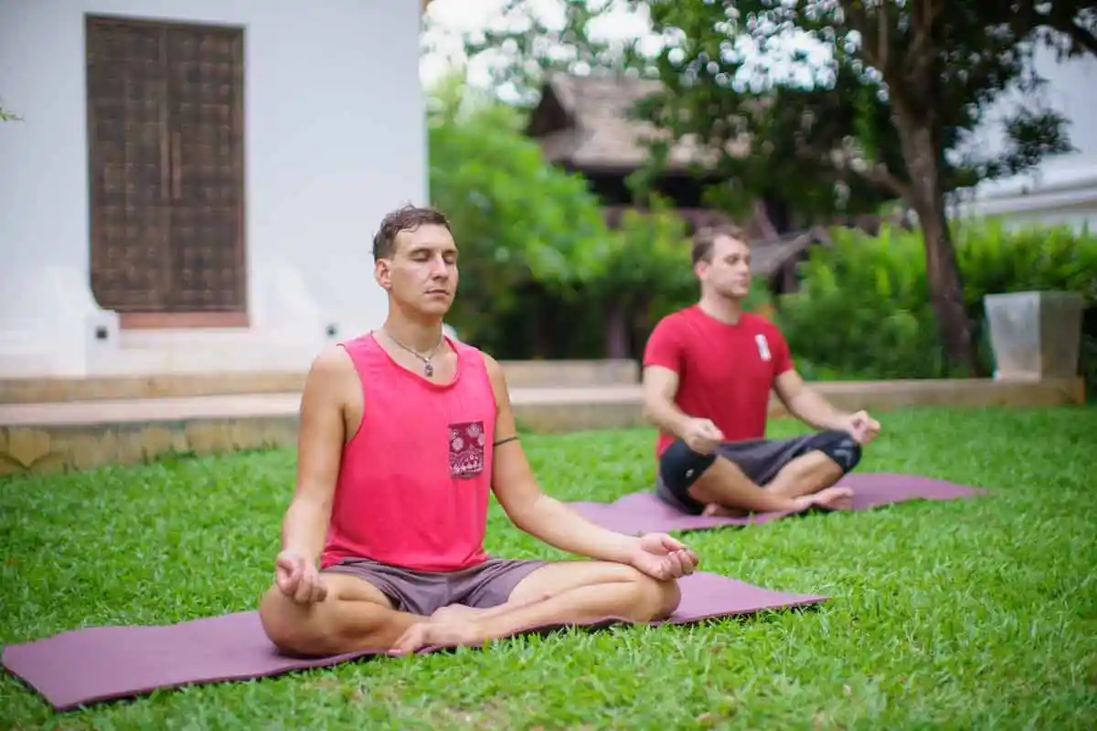Two male clients in red shirts meditating in the garden at The Dawn.