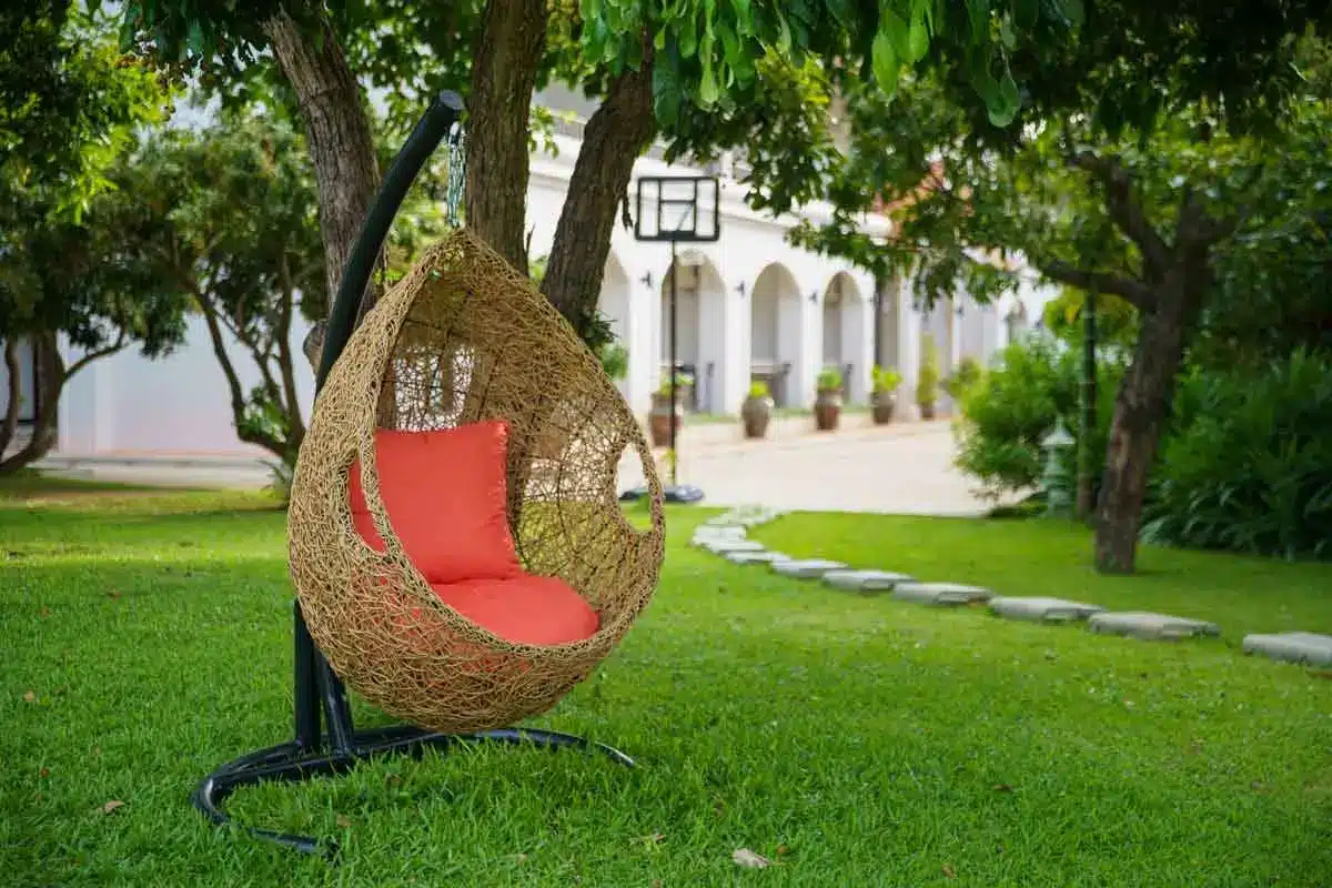 A photo of a hanging basket chair by a tree in a garden at The Dawn.