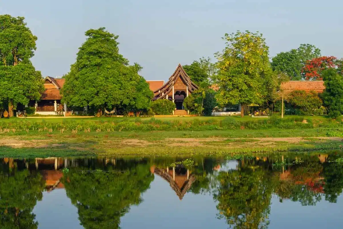 A view of the Dawn's pavilionsurrounded by trees across the river reflected in the calm river waters.